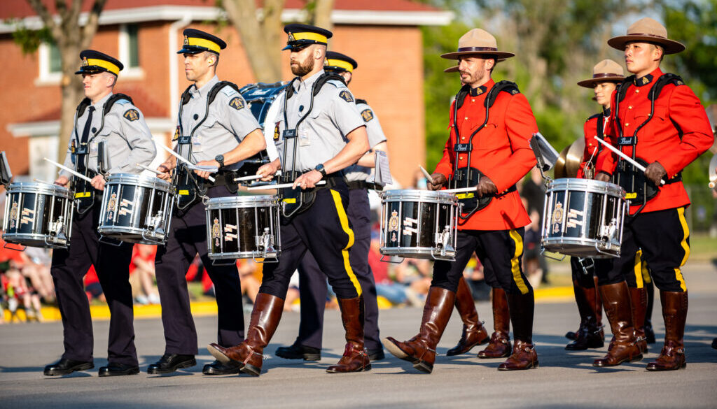 RCMP Members marching in uniform with drums in unison. 